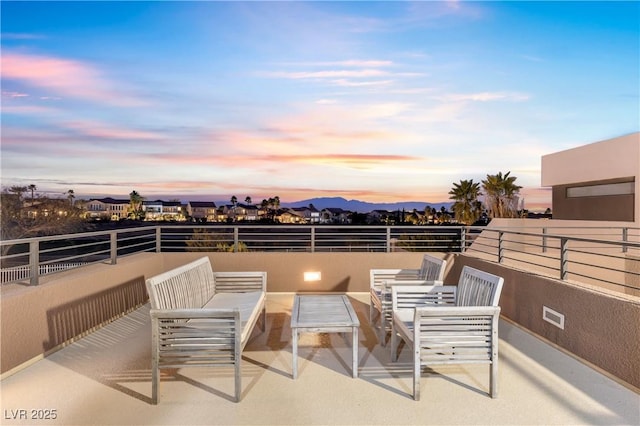 patio terrace at dusk with a balcony and an outdoor living space