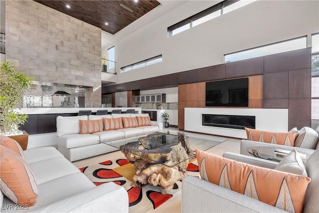 living room featuring a towering ceiling, wood ceiling, and light hardwood / wood-style floors