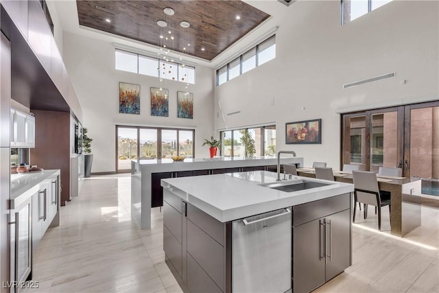 kitchen with a wealth of natural light, sink, a kitchen island with sink, and stainless steel dishwasher