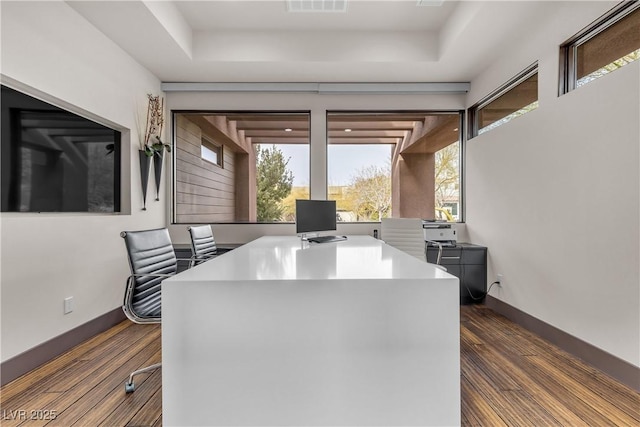 home office with dark hardwood / wood-style flooring and a raised ceiling