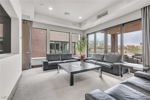 carpeted living room with a tray ceiling