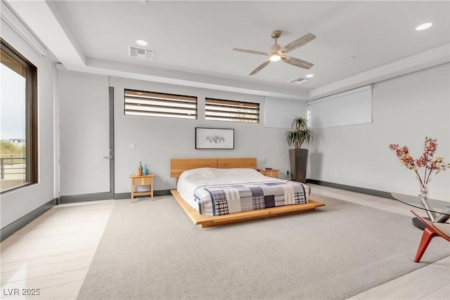 carpeted bedroom with ceiling fan and a tray ceiling