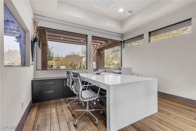 office with a raised ceiling, light hardwood / wood-style flooring, and built in desk