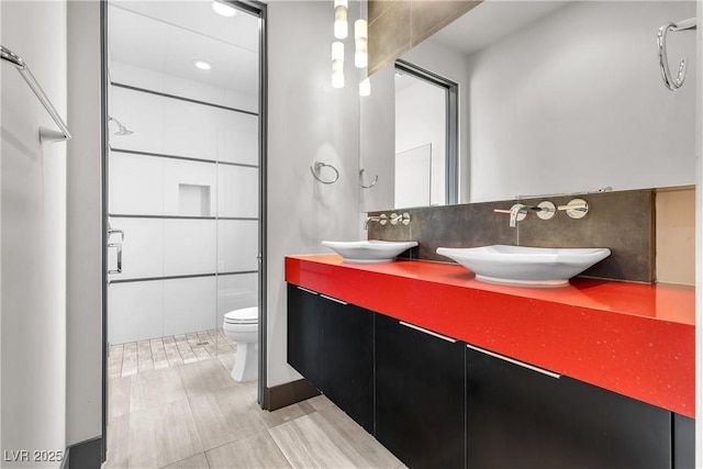 bathroom featuring tasteful backsplash, tile walls, vanity, toilet, and a shower with door