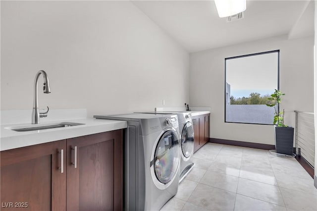 washroom with sink, light tile patterned floors, washing machine and dryer, and cabinets