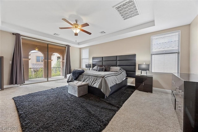 bedroom featuring ceiling fan, a tray ceiling, carpet, and access to outside