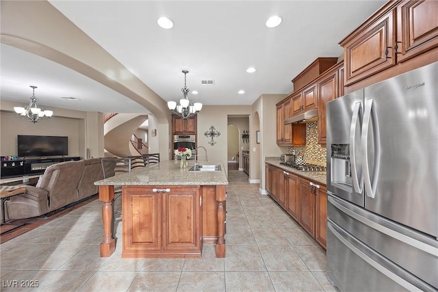 kitchen with an island with sink, sink, a kitchen breakfast bar, hanging light fixtures, and stainless steel appliances