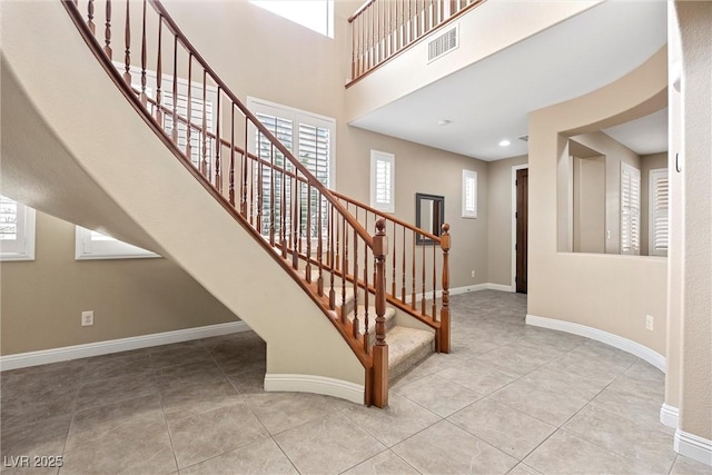 staircase featuring a towering ceiling and tile patterned floors