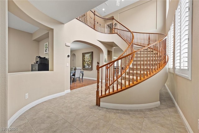 stairway featuring tile patterned floors and a high ceiling