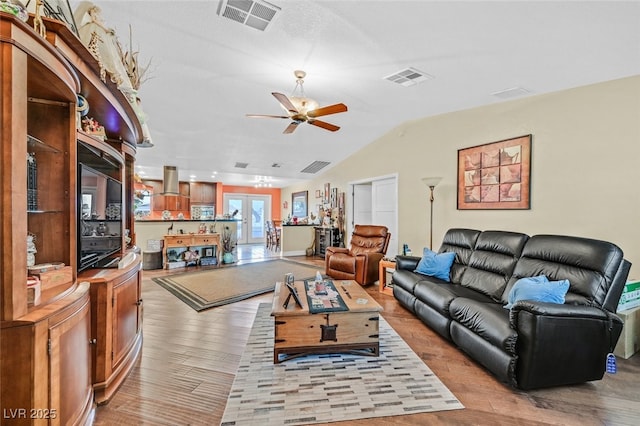 living room with ceiling fan, lofted ceiling, and light wood-type flooring