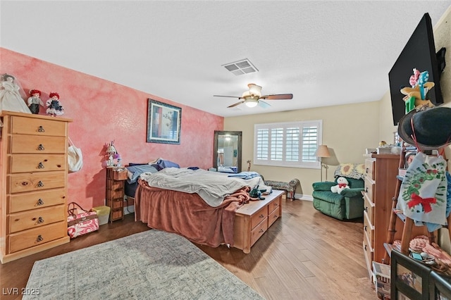 bedroom with ceiling fan, light hardwood / wood-style floors, and a textured ceiling