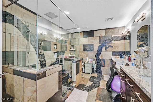 bathroom with hardwood / wood-style flooring, tile walls, tiled shower, vanity, and a textured ceiling