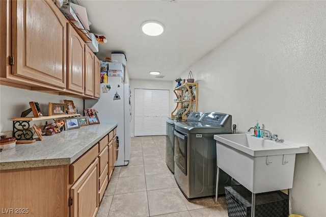 clothes washing area with cabinets, washing machine and clothes dryer, sink, and light tile patterned floors