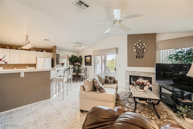 living room featuring ceiling fan, lofted ceiling, and a fireplace