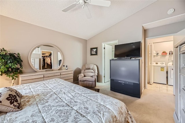 bedroom with lofted ceiling, washer and clothes dryer, ceiling fan, a textured ceiling, and light colored carpet