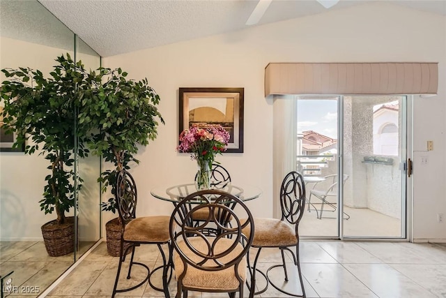 dining space featuring vaulted ceiling and a textured ceiling