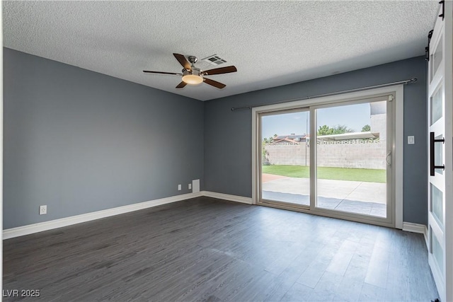 unfurnished room with a barn door, dark hardwood / wood-style floors, a textured ceiling, and ceiling fan