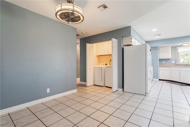 kitchen with light tile patterned flooring, white cabinetry, separate washer and dryer, sink, and white refrigerator