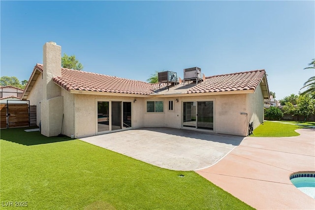 rear view of house with cooling unit, a yard, and a patio area