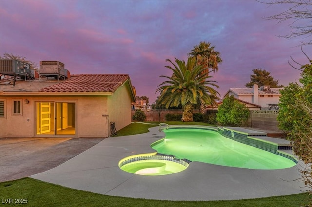 pool at dusk featuring an in ground hot tub, central AC, and a patio area