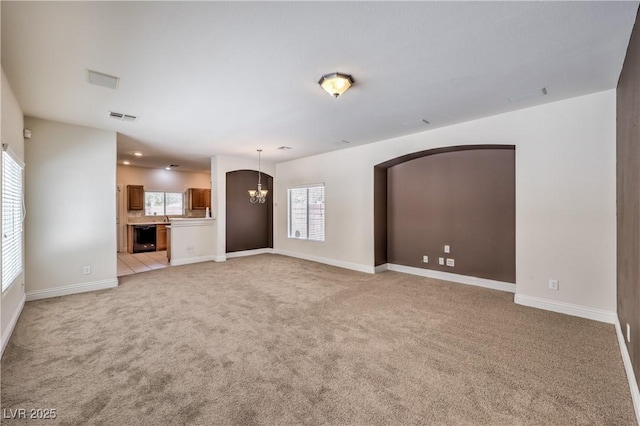 unfurnished living room with light colored carpet and a chandelier