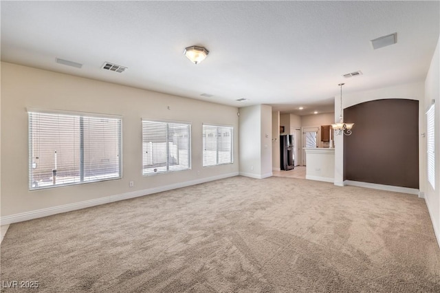 unfurnished living room with light carpet and an inviting chandelier