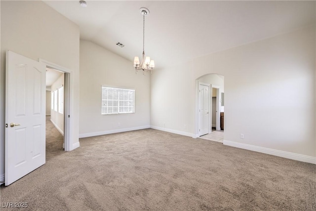 carpeted spare room featuring a notable chandelier and vaulted ceiling