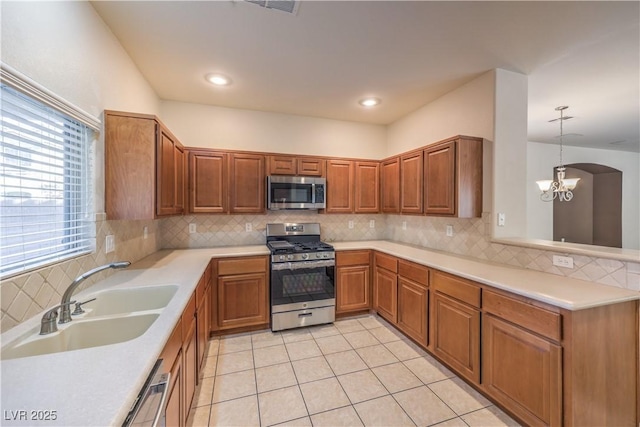 kitchen featuring sink, hanging light fixtures, stainless steel appliances, tasteful backsplash, and a chandelier