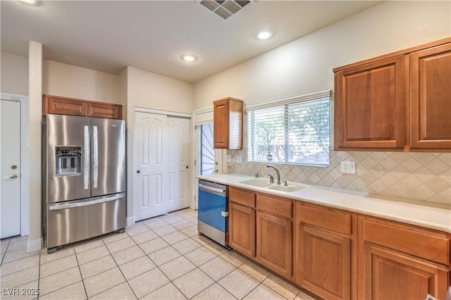 kitchen featuring stainless steel appliances, tasteful backsplash, sink, and light tile patterned floors