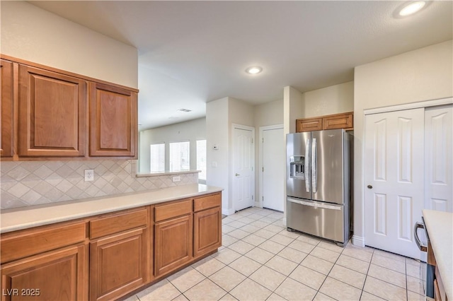 kitchen with stainless steel refrigerator with ice dispenser, light tile patterned floors, and backsplash