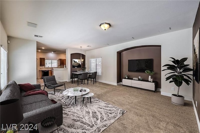 carpeted living room with an inviting chandelier and a healthy amount of sunlight