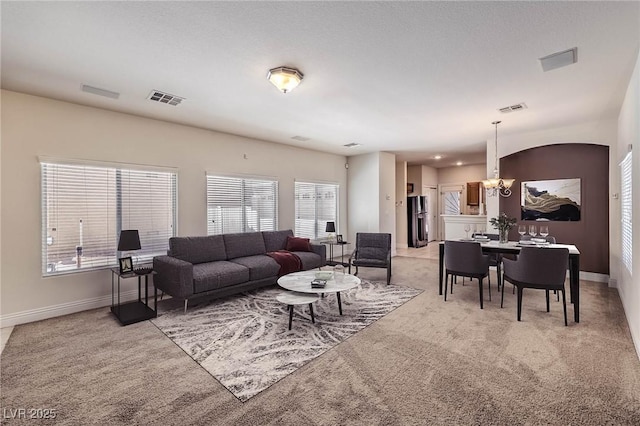 carpeted living room featuring a notable chandelier