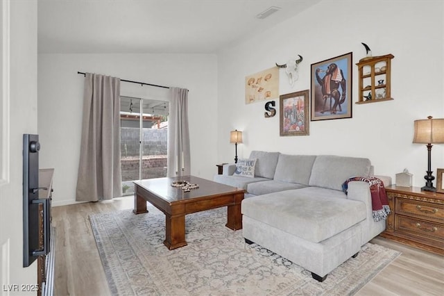 living room featuring vaulted ceiling and light hardwood / wood-style floors