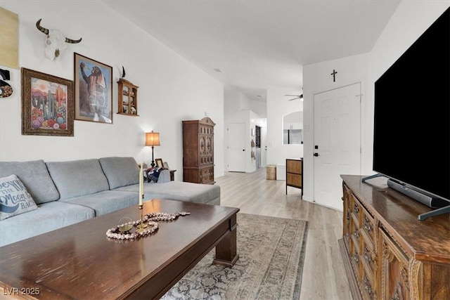 living room with ceiling fan, lofted ceiling, and light wood-type flooring