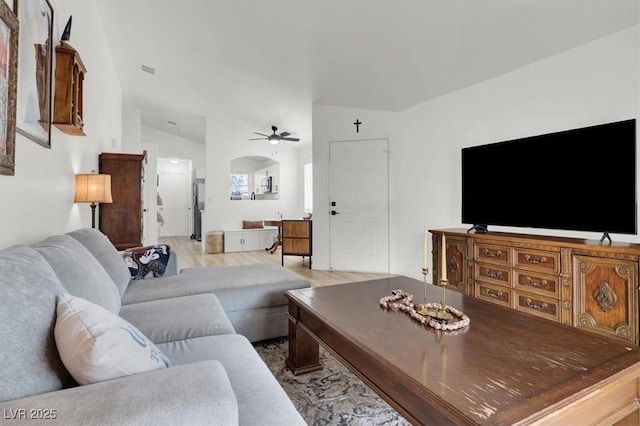 living room with ceiling fan, vaulted ceiling, and light hardwood / wood-style flooring