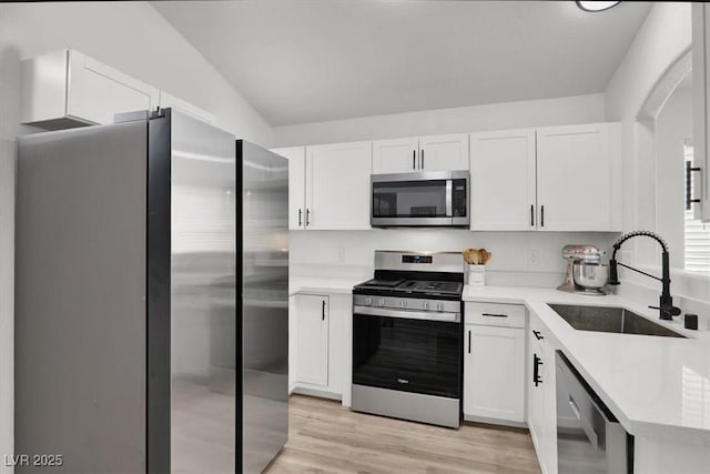 kitchen with stainless steel appliances, white cabinetry, sink, and light hardwood / wood-style floors