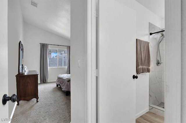 bathroom with a tile shower and vaulted ceiling