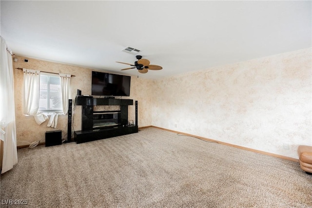 unfurnished living room featuring a premium fireplace, ceiling fan, and carpet