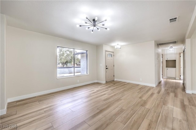 spare room featuring light hardwood / wood-style floors and a notable chandelier