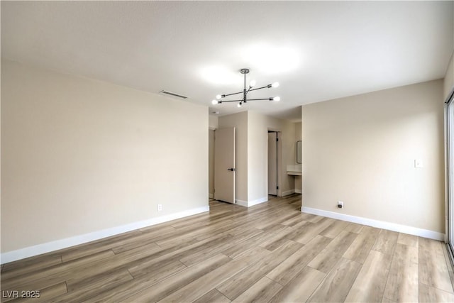 unfurnished room with a notable chandelier and light hardwood / wood-style flooring