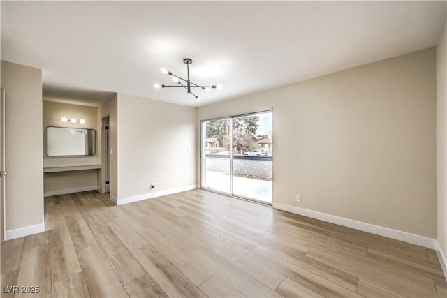 unfurnished room with a chandelier and light hardwood / wood-style floors