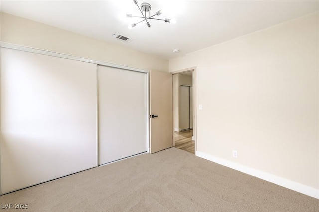 unfurnished bedroom featuring light carpet and a closet