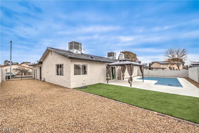 back of property with a gazebo, central AC unit, a patio, and a lawn