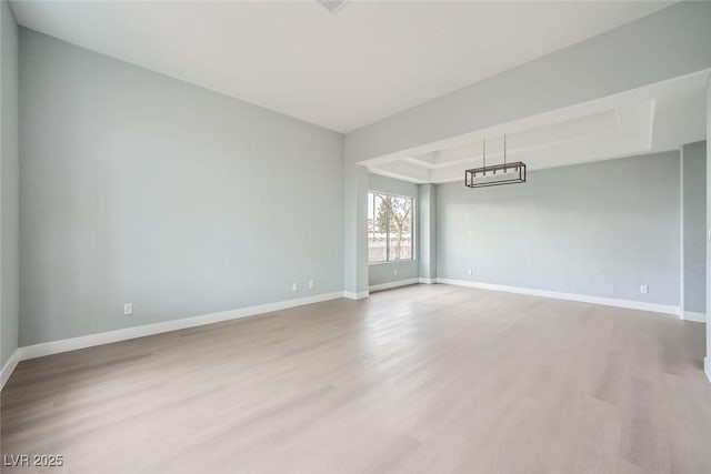 unfurnished room featuring hardwood / wood-style floors, an inviting chandelier, and a tray ceiling