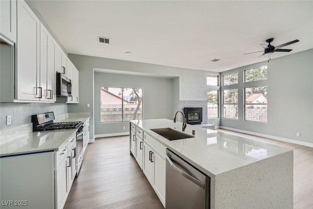 kitchen with white cabinetry, sink, stainless steel appliances, and light stone countertops