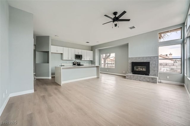 unfurnished living room featuring sink, light hardwood / wood-style flooring, and ceiling fan