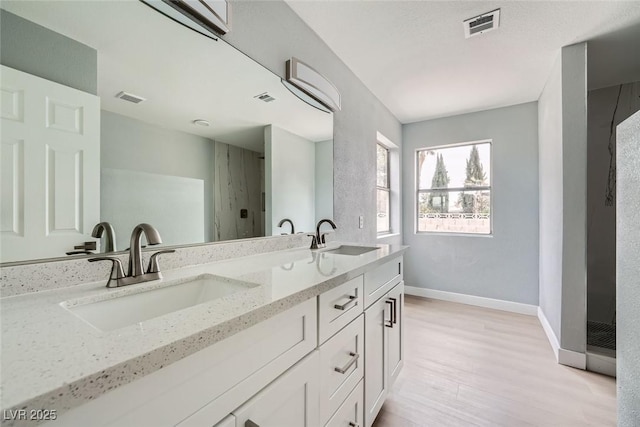 bathroom with hardwood / wood-style flooring, vanity, and an AC wall unit