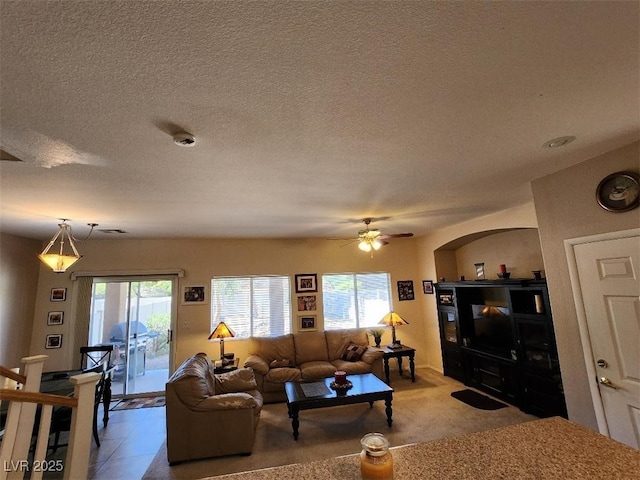 living room featuring ceiling fan and a textured ceiling