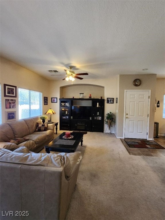 carpeted living room featuring ceiling fan and a textured ceiling