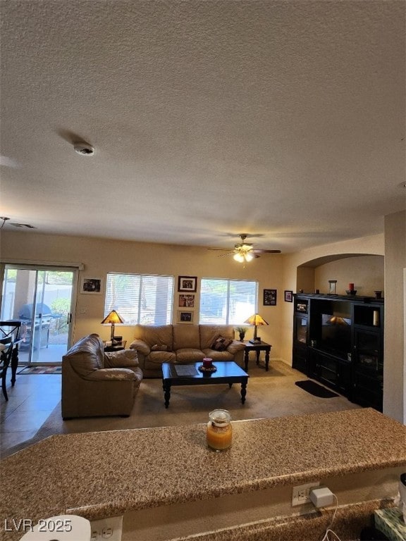 living room featuring ceiling fan, a textured ceiling, and a wealth of natural light